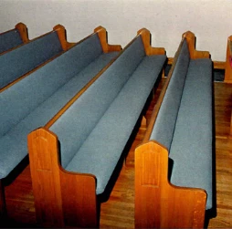 The same wooden pews after re-upholstery in blue-gray fabric